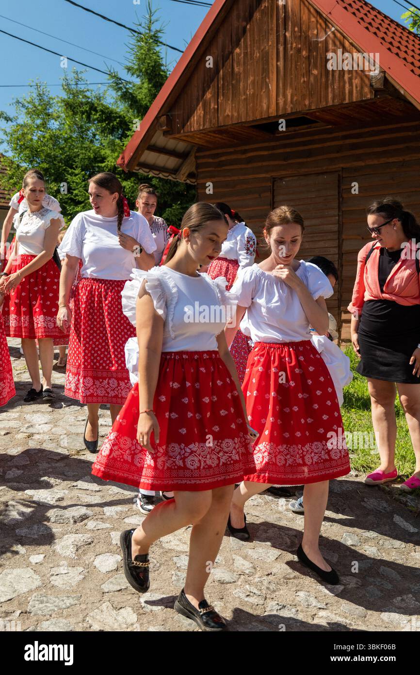 Kindergartenlehrer in traditionellen Sliac Volkstrachten nähern sich langsam der Bühne beim Juniales Folk Festival Stockfoto