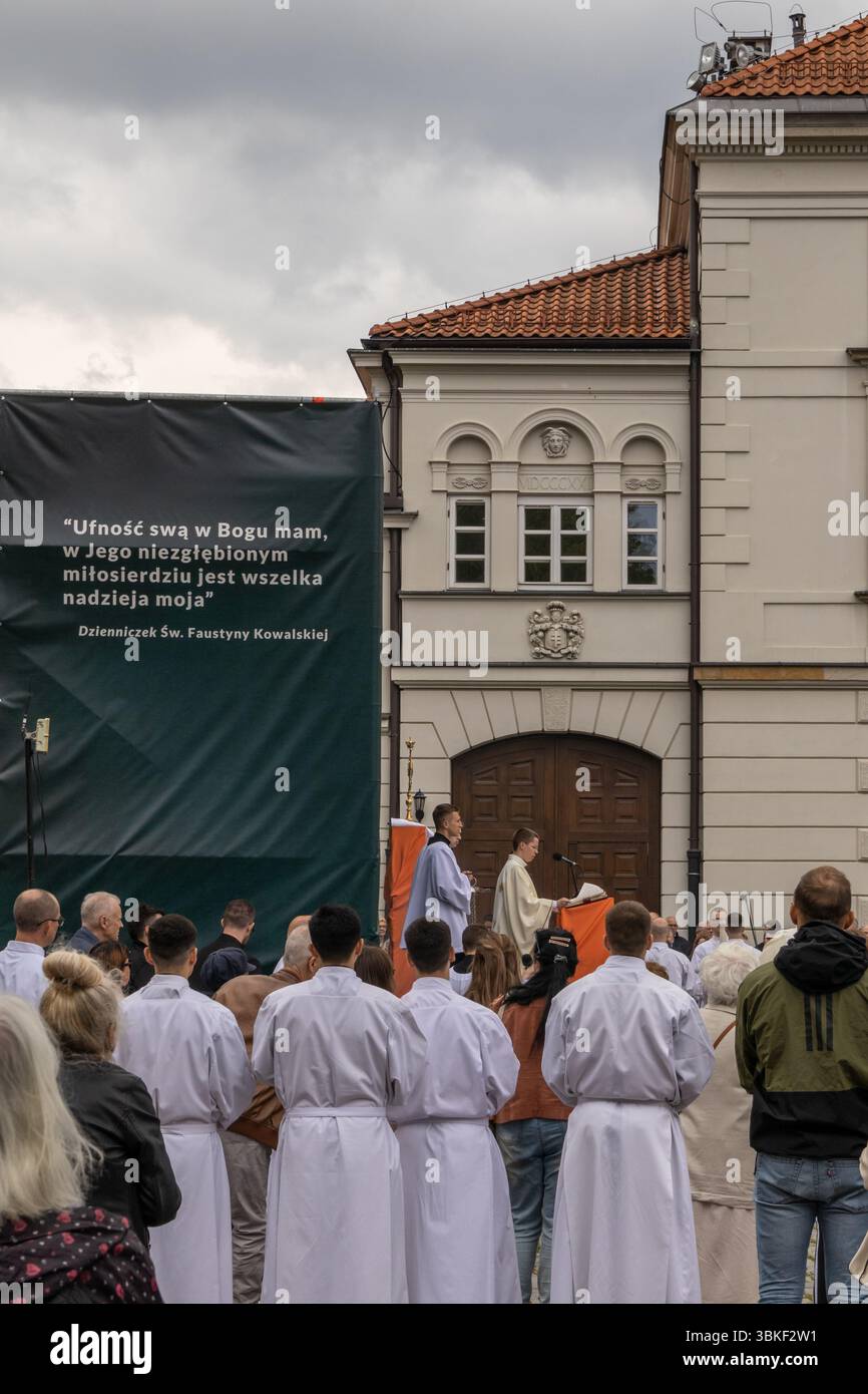 WHO: Gruppe katholischer Geistlicher und Pfarrer in weißen Alben und liturgischen Gewändern. WAS: Freiluftprozession mit dem Allerheiligsten Stockfoto
