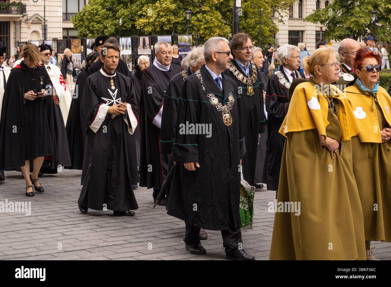 Katholischer Geistlicher und Laienteilnehmer tragen das Allerheiligste in traditionellen Gewändern in einer Monstranz während einer Freiluftprozession. Das Ereignis Stockfoto