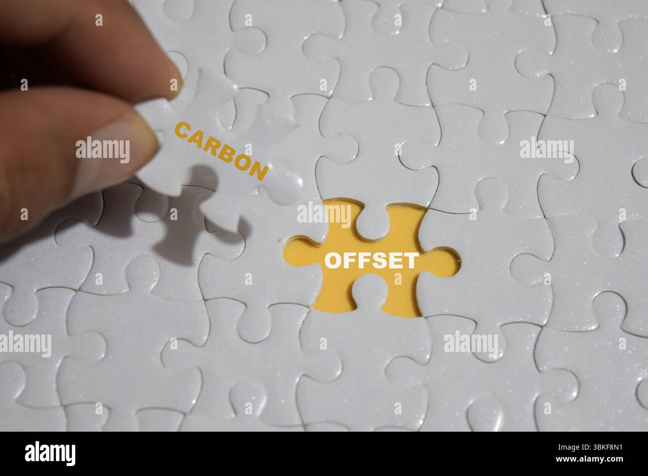 Hand hält ein Puzzlestück mit Wort Carbon und Offset. Stockfoto