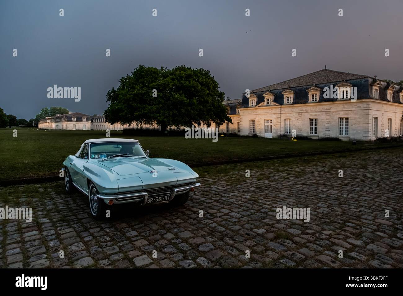 Ein hellblauer Chevrolet Corvette C2 Sting Ray (hergestellt 1963–1967) auf den Pflastersteinen vor der Corderie Royale in Rochefort in der Dämmerung, vor einem dramatisch bewölkten Himmel. Der Wagen mit dem französischen Kennzeichen BR-581-RT war Teil eines Oldtimer-Treffens auf dem Gelände des ehemaligen Marinearsenals. Rue Jean-Baptiste Audebert, Rochefort, Charente-Maritime, Nouvelle-Aquitaine, Frankreich Stockfoto