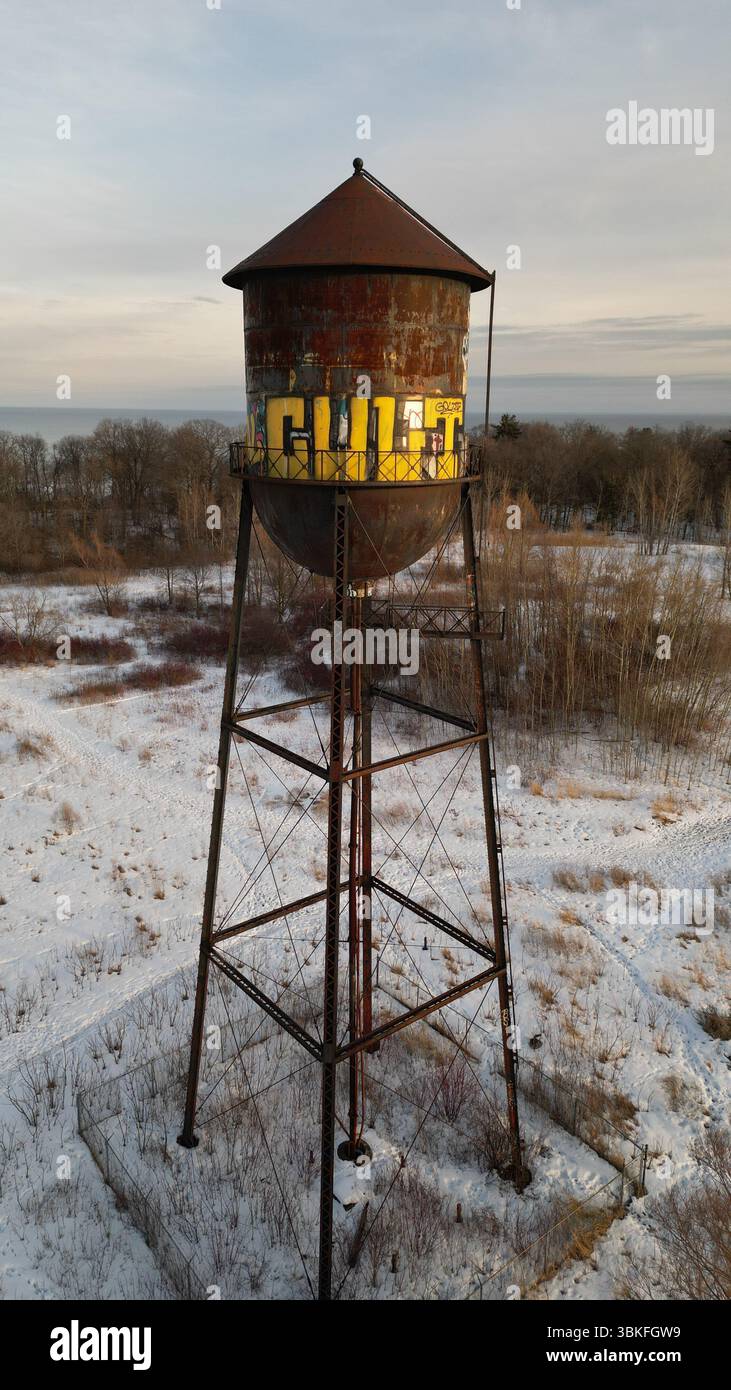 Winteransicht einer verlassenen alten Mühle mit schneebedecktem umliegenden Land, verblassten Wandmalereien und einem verwitterten korrosiven Turm Stockfoto