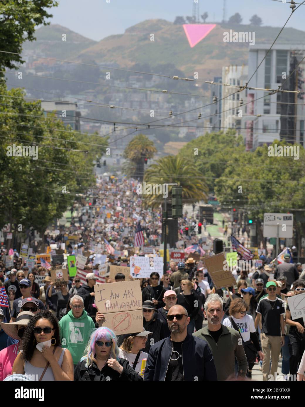 Während des No Kings Protests von 2025 unter dem berühmten Pink Triangle spaziert eine riesige Menge Demonstranten die Market Street in San Francisco entlang. Stockfoto