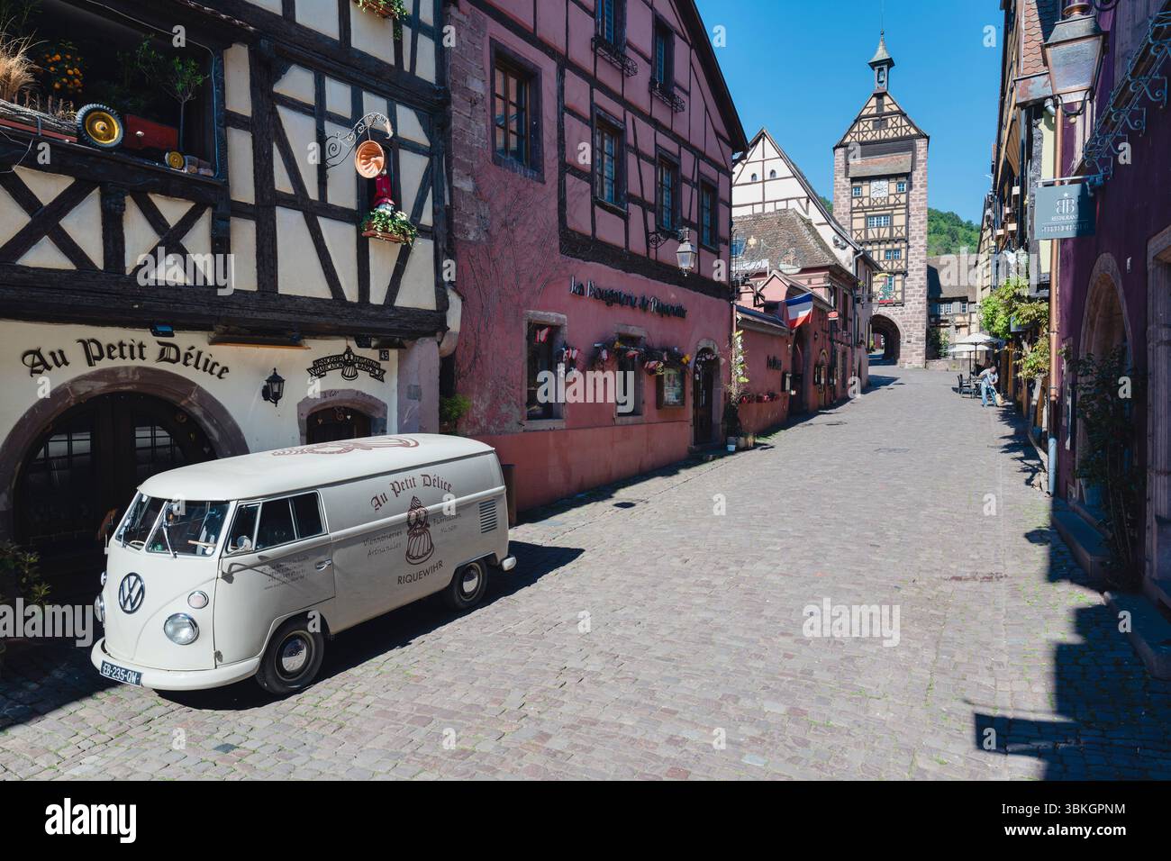Vor Fachwerkhäusern und dem Stadttor von Dolder steht ein alter VW Bulli Van in der Altstadt von Riquewihr, Elsass, Frankreich Stockfoto