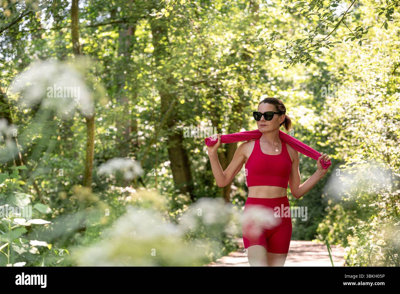 Frau, die im Sommer in Aktivkleidung auf einem Waldweg trainiert Stockfoto