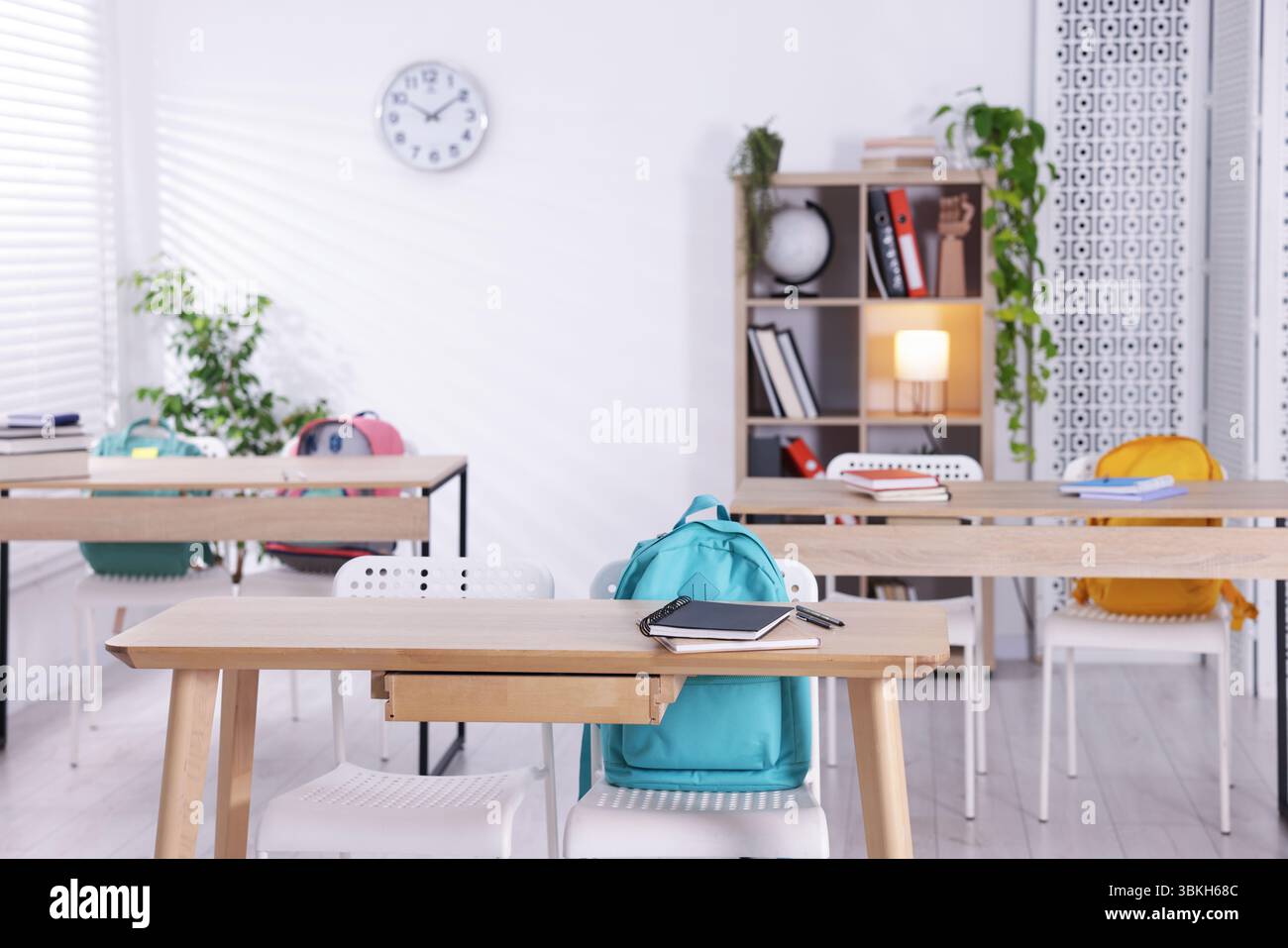 Leerer Klassenzimmer mit Holzschreibtischen, Stühlen und Rucksäcken Stockfoto