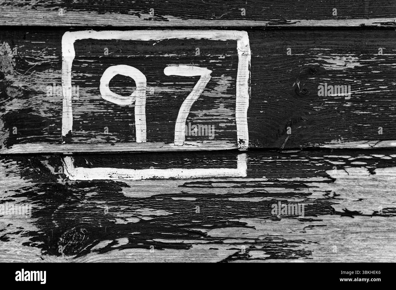Nummer 97 auf Holz gemalt mit abblätternder Farbe in Schwarz-weiß Stockfoto