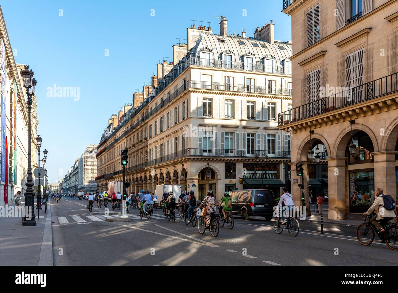Radfahrer an einem frühen sonnigen Morgen in der Rue de Rivoli, im 1. Arrondissement von Paris. Das tägliche Pariser Leben. Straßenszene. Haussmann-Apartments Stockfoto