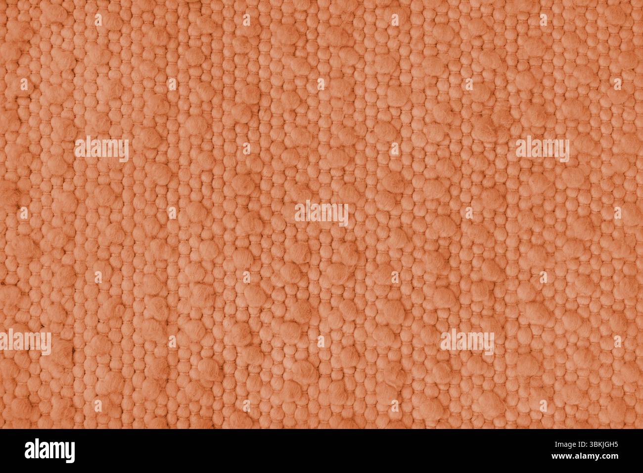 Textur aus orangefarbenem Teppichgewebe mit grober Textur. Oberfläche, Struktur von Polstern oder Teppichmaterial, Stoffhintergrund in Nahaufnahme, Makr Stockfoto
