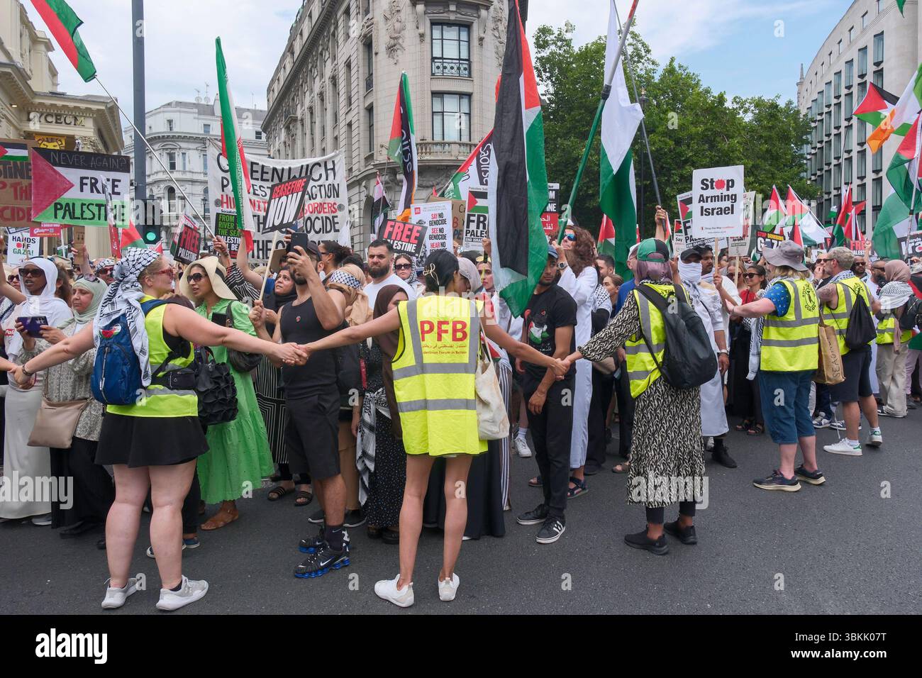 London, Großbritannien. Juni 2025. Tausende palästinensischer Solidaritätsdemonstratoren marschieren durch die Londoner Innenstadt. Ein statischer Gegenprotest, der von der pro-israelischen Gruppe Stop the Hate organisiert wird, findet in der Nähe der marschroute statt. Im Bild: Freiwillige Marshals helfen dabei, den palästinensischen solidaritätsmarsch in Ordnung zu halten, während er nahe am Gegenprotest der pro-israelischen Aktivisten vorbeigeht. Stockfoto