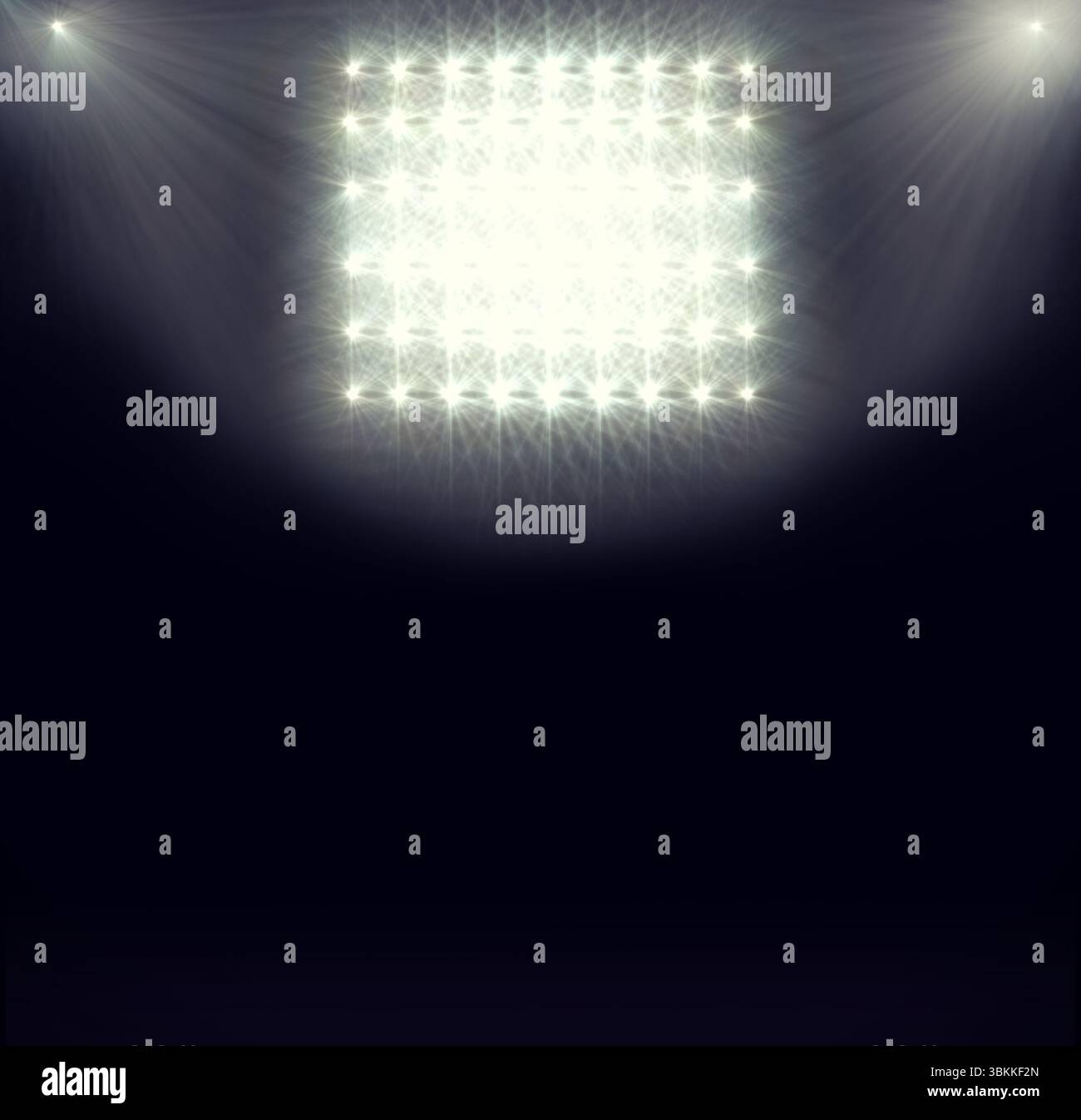 Ein flaches Gitter aus Stadionflutlichtern wirft helle Starburstbalken über den dunklen Boden der Arena Stockfoto