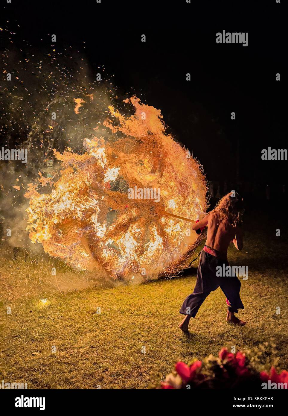 Der Mensch schiebt ein großes brennendes Rad vom Hügel als traditionelles lettisches Ritual zur Hochsommer- oder Sonnensonnenfeier Stockfoto