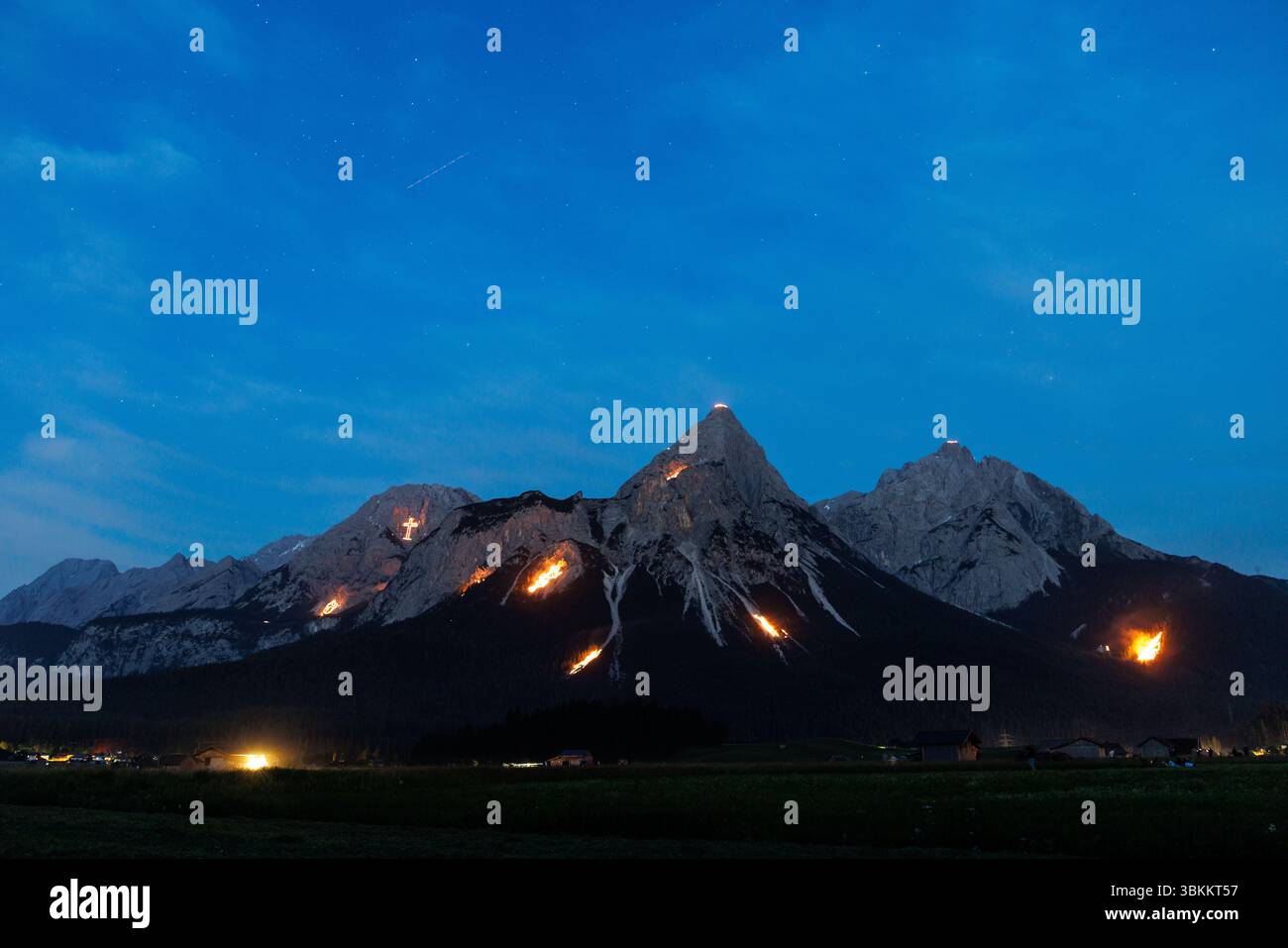 Lermoos, Österreich. Lermoos, Österreich. Juni 2025. In der Tiroler Zugspitz Arena im Ehrwald Lermoos- und Biberwiertalbecken in Tirol (Österreich) sind am 21.06.2025 zur Sommersonnenwende zahlreiche Brände zu sehen. Das Bild zeigt die Ehrwalder Sonnenspitze in der Mieminger Kette. Jedes Jahr werden in der Region der längste Tag und die kürzeste Nacht mit spektakulärem Feuerwerk gefeiert. In der Abenddämmerung zünden sogenannte Bergfeurer die Mittsommerfeuer an, die dann bis in die Nacht brennen. Quelle: dpa Picture Alliance/Alamy Live News Stockfoto