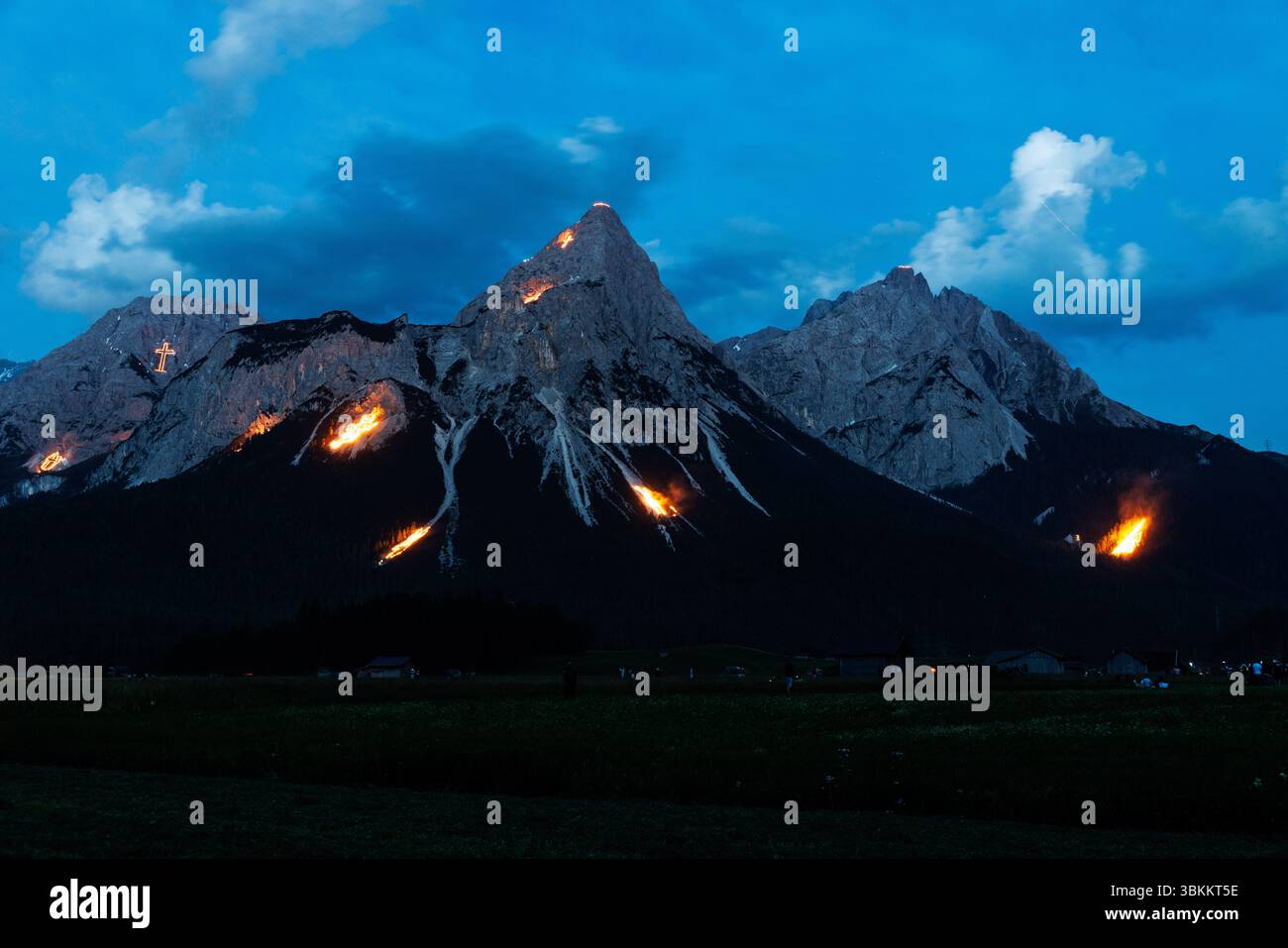 Lermoos, Österreich. Lermoos, Österreich. Juni 2025. In der Tiroler Zugspitz Arena im Ehrwald Lermoos- und Biberwiertalbecken in Tirol (Österreich) sind am 21.06.2025 zur Sommersonnenwende zahlreiche Brände zu sehen. Das Bild zeigt die Ehrwalder Sonnenspitze in der Mieminger Kette. Jedes Jahr werden in der Region der längste Tag und die kürzeste Nacht mit spektakulärem Feuerwerk gefeiert. In der Abenddämmerung zünden sogenannte Bergfeurer die Mittsommerfeuer an, die dann bis in die Nacht brennen. Quelle: dpa Picture Alliance/Alamy Live News Stockfoto