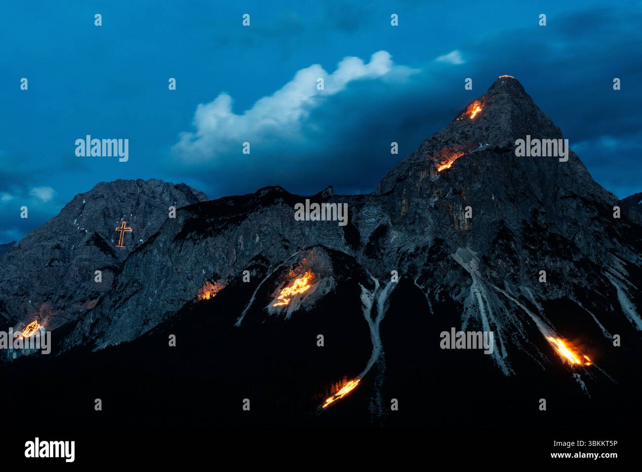 Lermoos, Österreich. Lermoos, Österreich. Juni 2025. In der Tiroler Zugspitz Arena im Ehrwald Lermoos- und Biberwiertalbecken in Tirol (Österreich) sind am 21.06.2025 zur Sommersonnenwende zahlreiche Brände zu sehen. Das Bild zeigt die Ehrwalder Sonnenspitze in der Mieminger Kette. Jedes Jahr werden in der Region der längste Tag und die kürzeste Nacht mit spektakulärem Feuerwerk gefeiert. In der Abenddämmerung zünden sogenannte Bergfeurer die Mittsommerfeuer an, die dann bis in die Nacht brennen. Quelle: dpa Picture Alliance/Alamy Live News Stockfoto
