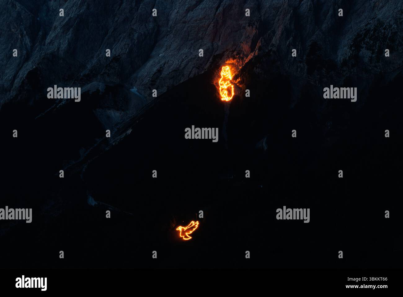 Lermoos, Österreich. 21. Juni 2025, Österreich, Lermoos: Zur Sommersonnenwende sind am 21.06.2025 in der Tiroler Zugspitz Arena im Ehrwald Lermoos- und Biberwiertalbecken in Tirol zahlreiche Brände zu sehen. Das Bild zeigt das Wettersteingebirge mit der Tiroler Seite der Zugspitze, auf der die Brände ein Murmeltier und eine Taube des Friedens bilden. Jedes Jahr werden in der Region der längste Tag und die kürzeste Nacht mit spektakulären Feuermotiven gefeiert. In der Abenddämmerung zünden sogenannte Bergfeurer die Mittsommerfeuer an, die dann bis in die Nacht brennen. Kredit: dpa Picture allian Stockfoto