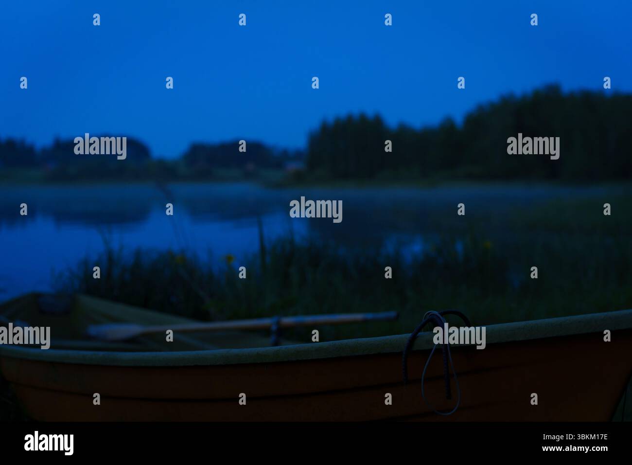 Ein stiller See in der Mittsommernacht mit Nahaufnahme eines Ruderbootes an der Küste. Stockfoto