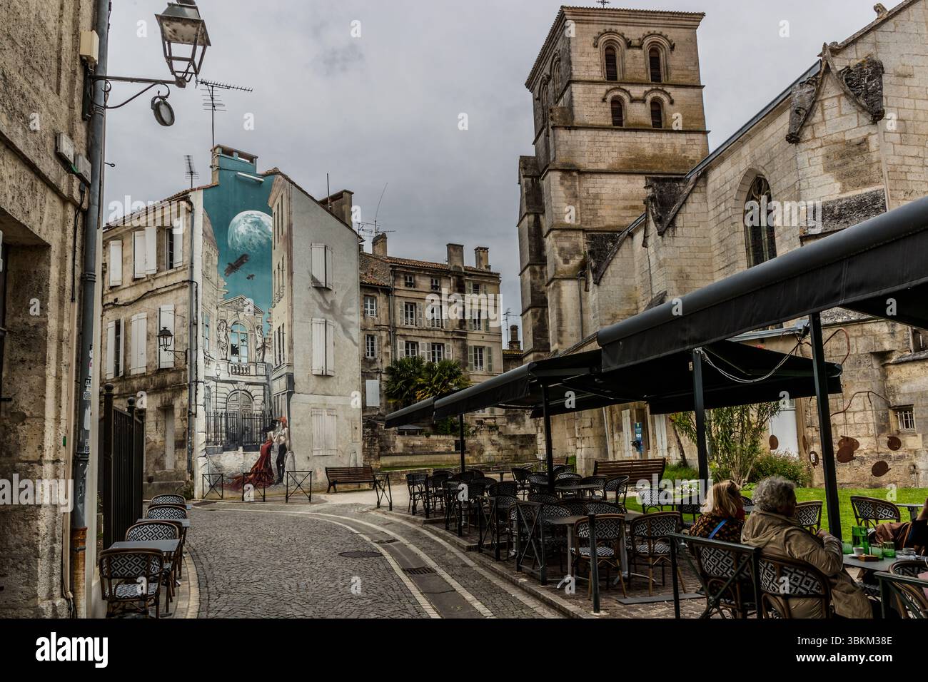 Ein Wandbild zeigt eine Szene mit einem Paar, einem Flugzeug und einem Mond vor dem Hintergrund historischer Architektur. Es ist ein Beispiel für Straßenkunst, die die Stadt verschönert und die Geschichte und Kultur der Region widerspiegelt. Angoulême ist seit 2019 als UNESCO-Kreativstadt in der Kategorie Literatur anerkannt. Rue Sainte-Marie, Angoulême, Nouvelle-Aquitaine, Frankreich Stockfoto