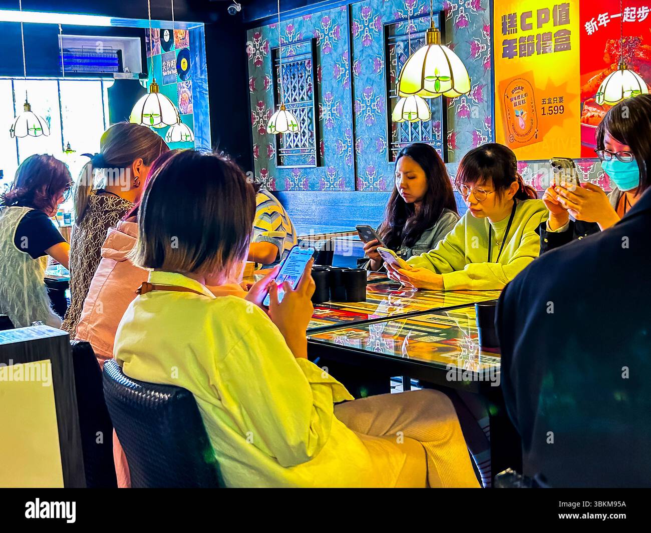 Taipei, Taiwan, Gruppe Junge Leute, sitzen am Tisch, schauen auf Smartphones, lokales Hong Kongese Restaurant, 'Jiu Long Bing Shi', 'Kowloon Cafe' Stockfoto