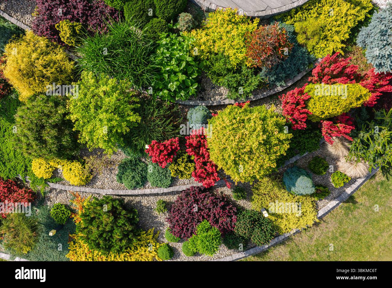 Ein wunderschön gestalteter Garten bietet eine Vielzahl von bunten Pflanzen und Sträuchern, die eine auffällige Landschaft schaffen. Das leuchtende Laub zeigt c Stockfoto
