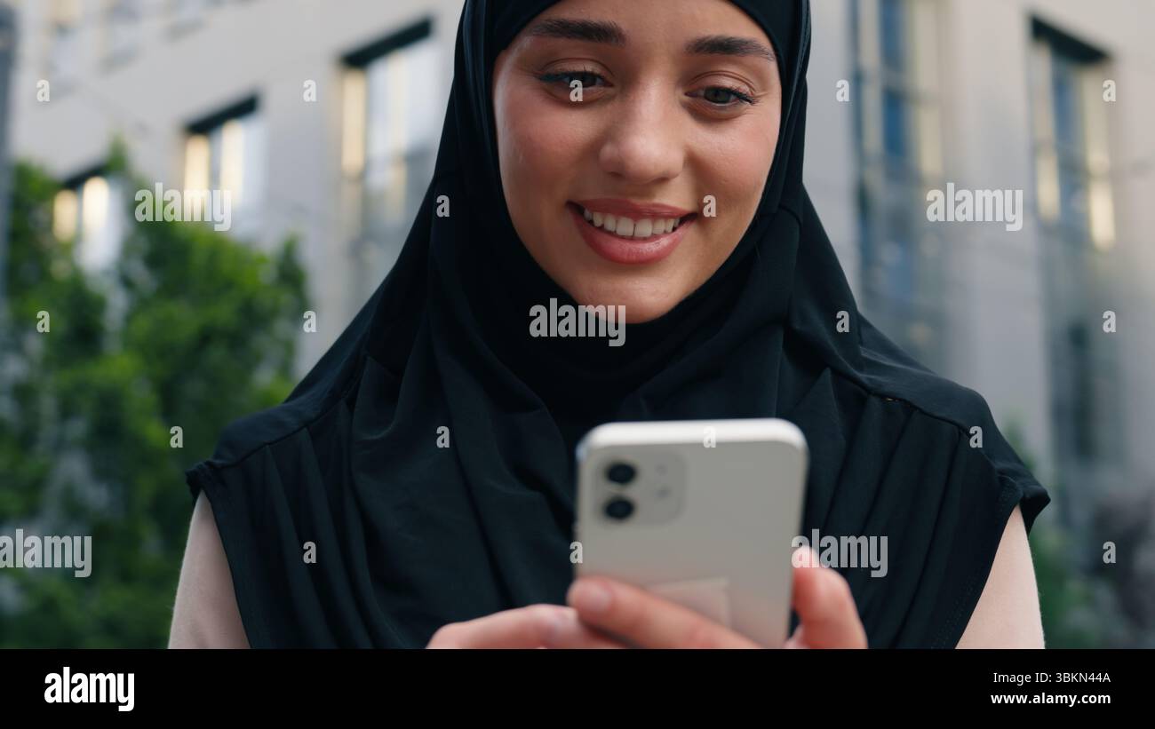 Porträt glücklich lächelnde muslimische positive islamische Frau trägt Hijab Geschäftsfrau Geschäftsfrau weibliches Mädchen in der Stadt draußen in der Innenstadt mit Handy Stockfoto