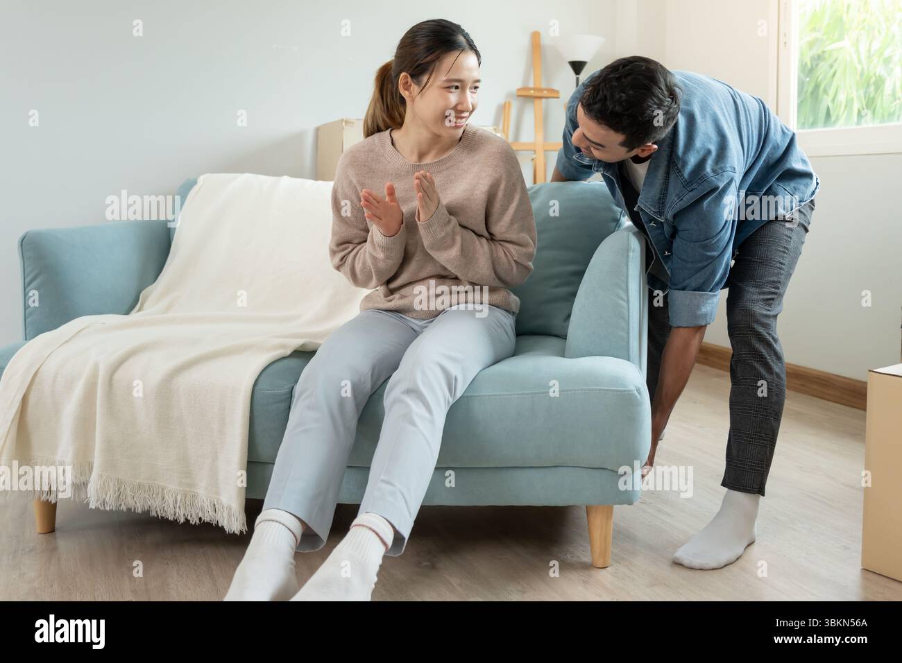Umzug, Umzug. Die Frau fühlt sich gut und neckt ihren Mann, im Zimmer war eine Pappschachtel mit persönlichen Sachen und Möbeln Stockfoto