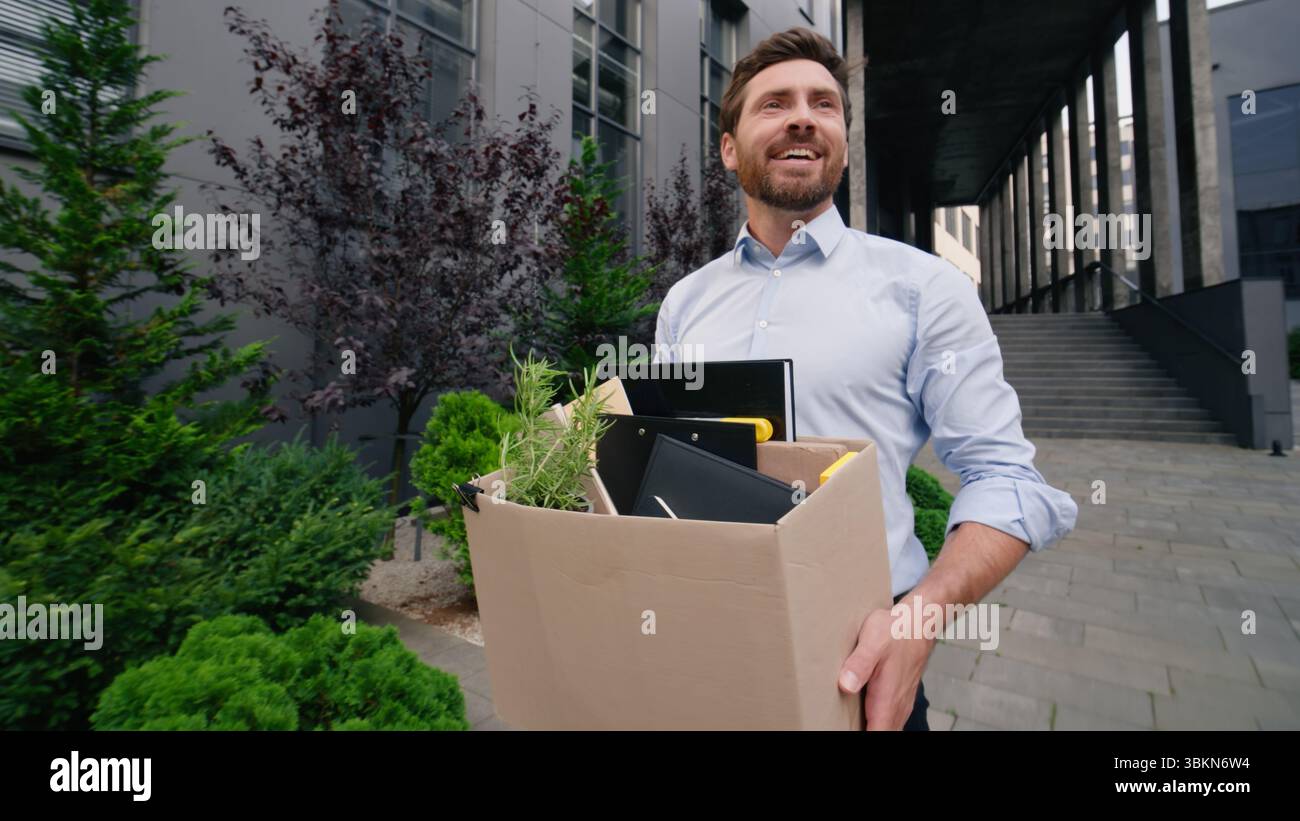 Glückliches Singen lächelnd Gehen in Stadt Mann Geschäftsmann männlicher Kerl Geschäft entlassen Büro beenden Firma arbeiten halten Tragen Entlassungsbox neu Stockfoto