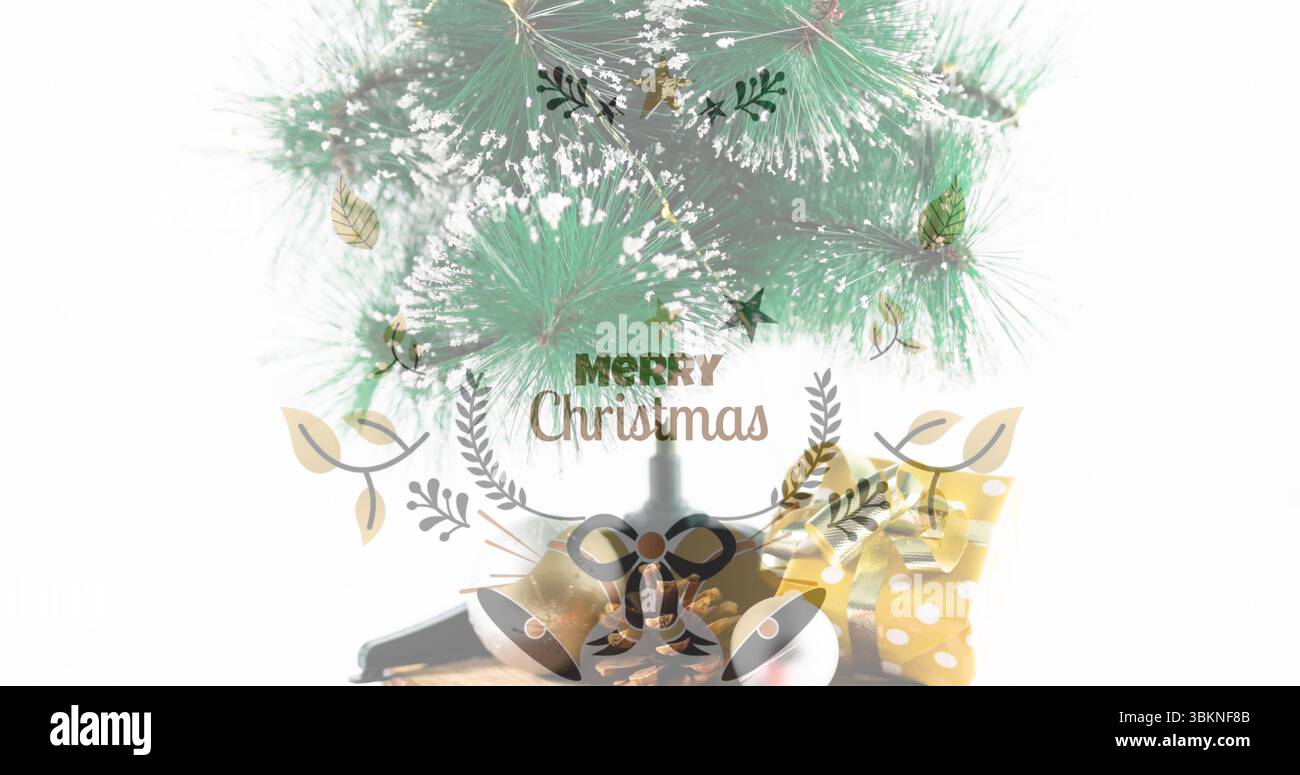 Mit Tannenzweigen, die falschen Schnee auf Holztisch stauben, fröhlicher Weihnachtstext mit Glocken, Band Stockfoto
