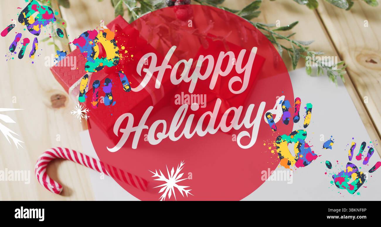 Auf der Tischplatte ist ein Happy Holidays-Banner mit Zuckerrohr, immergrünem Zweig, Handabdrücken und Papier zu sehen Stockfoto