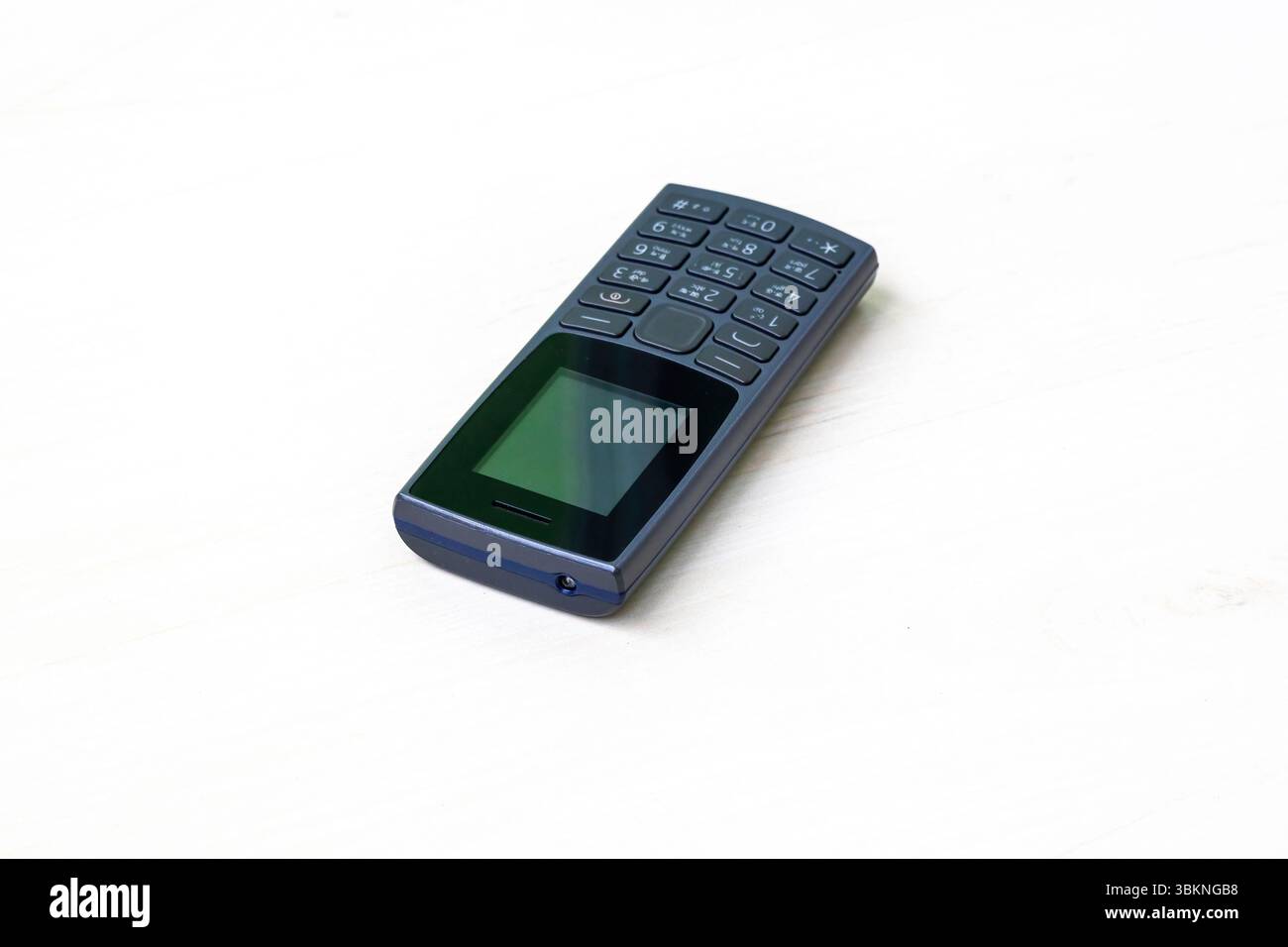 Klassisches schwarzes Tastentelefon, weißer Hintergrund. Altes Funktionstelefon mit Taschenlampenfunktion. Stockfoto