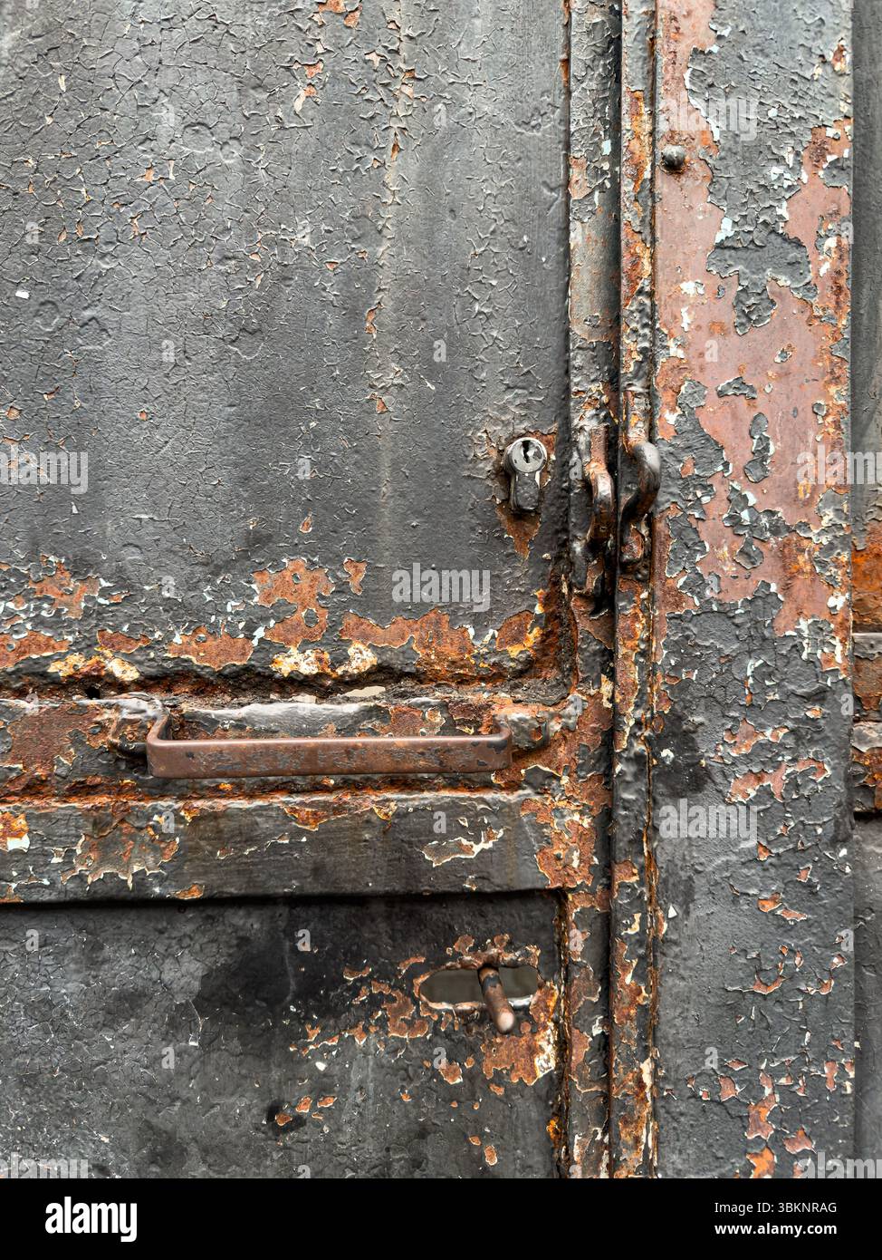 Nahaufnahme einer verwitterten Metalltür mit abblätternder Farbe, Roststruktur und Industriegriff. Ideal als Hintergrund oder Textur. Keine Personen. Stockfoto