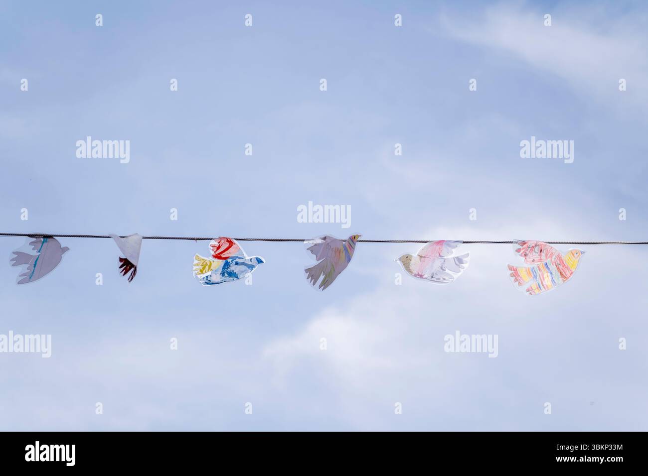 Ein atemberaubendes Schauspiel farbenfroher Papierköpfe, die elegant an einem hellen blauen Himmel hängen Stockfoto
