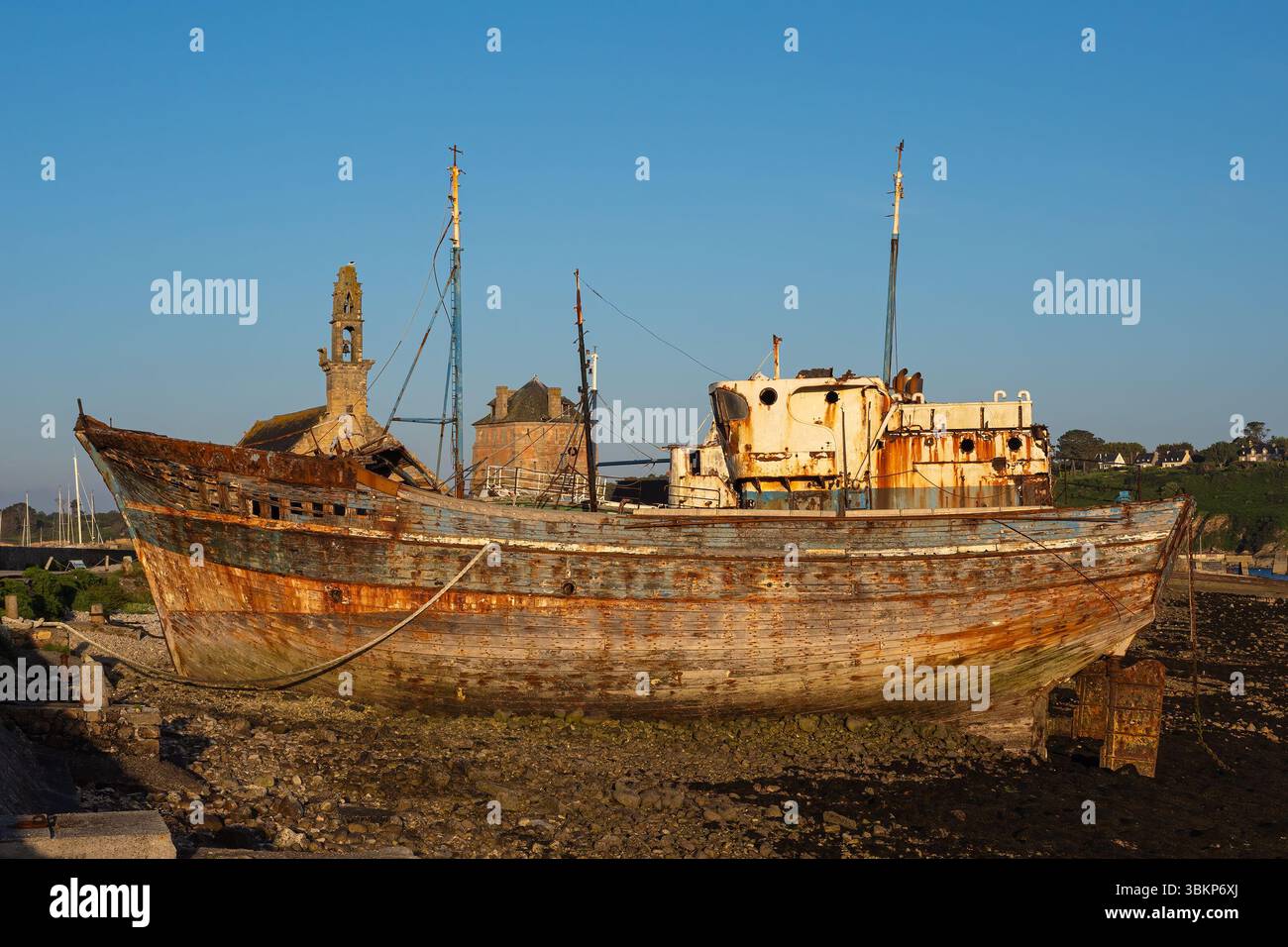 Alte verwitterte und verfallene Holzfischboote auf dem historischen Bootsfriedhof in Camaret-sur-Mer in der Bretagne, Frankreich, in der Abenddämmerung unter klarem Himmel. Stockfoto
