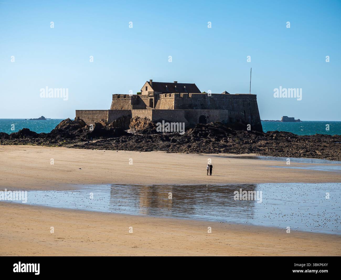 Sehen Sie sich das Fort National aus dem 17. Jahrhundert von Vauban in Saint-Malo an, mit einem Paar, das bei Ebbe spazieren geht. Historische Küstenverteidigung in der Bretagne, Fran Stockfoto