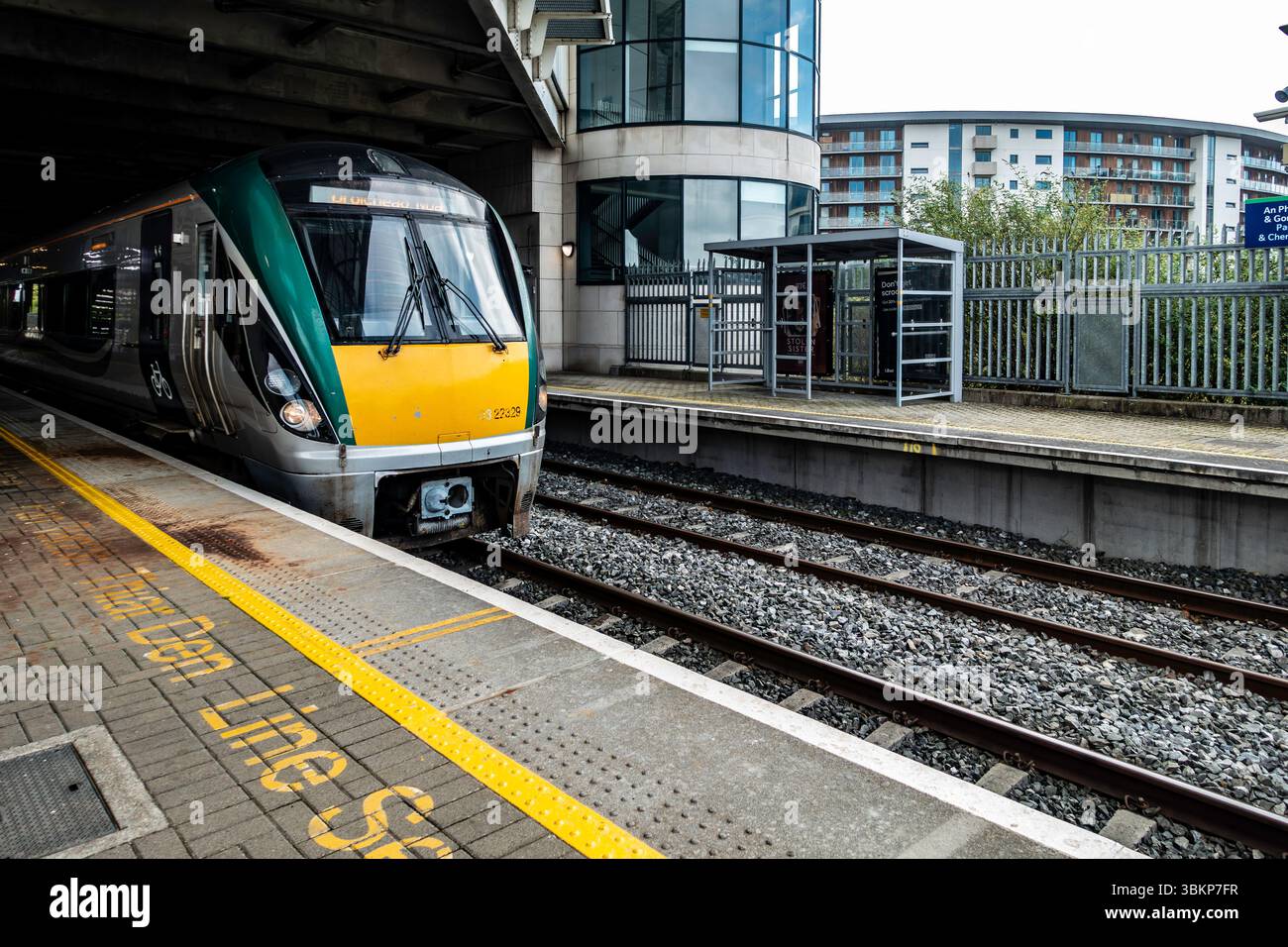 Irish Rail InterCity-Zug nach Newbridge, County Kildare, Parkwest und Cherry Orchard Station, Dublin, mit Bahnsteigmarkierungen und städtischer Kulisse. Stockfoto