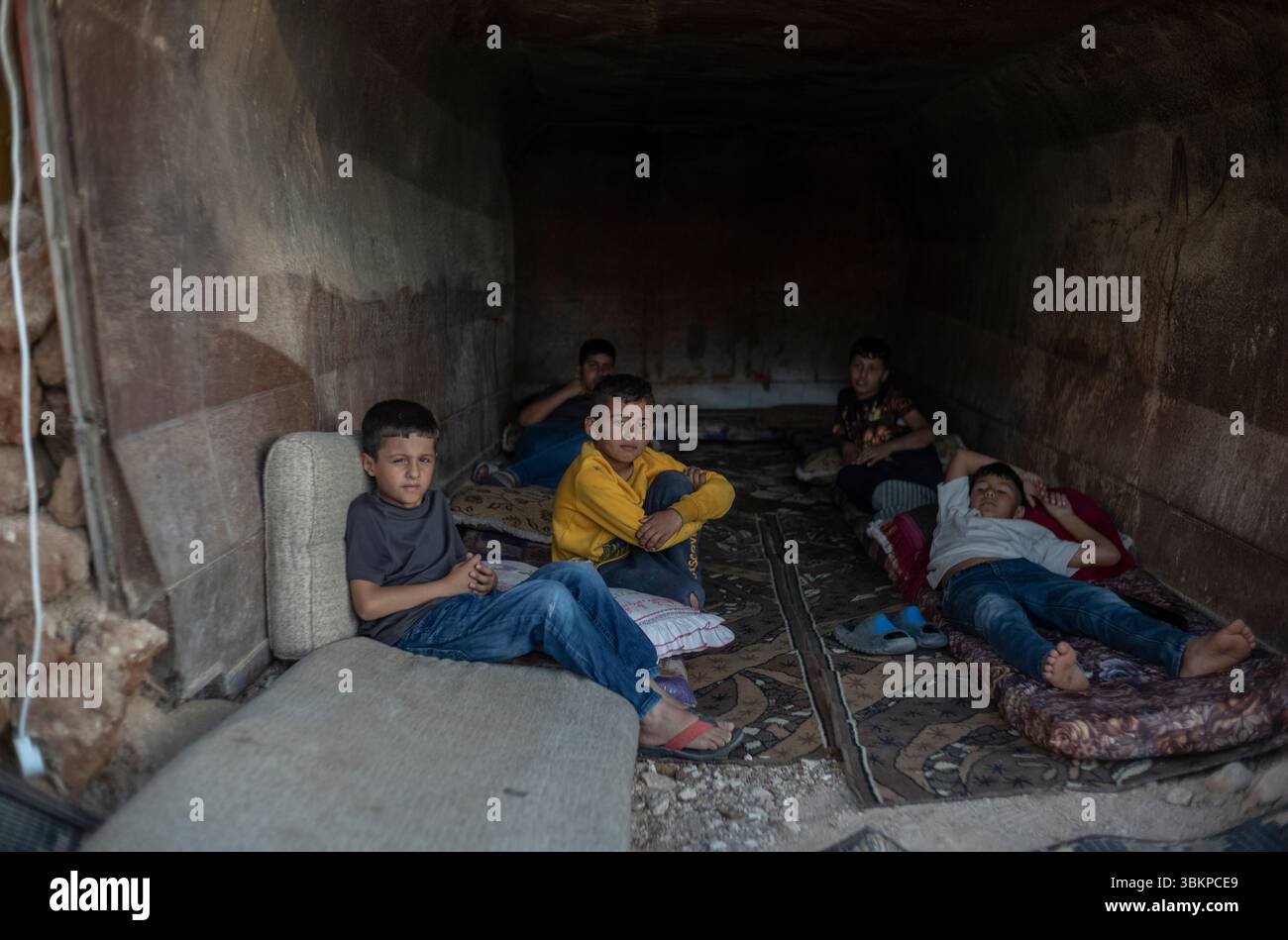 Al Furaa, Israel. Juni 2025. Die Kinder versammeln sich im provisorischen Bombenschutzraum, der aus in Schmutz vergrabenem Schotterwagen gebaut wurde, um sie vor eintreffenden iranischen Raketen im unbekannten Dorf Al-Furaa zu schützen. Die Negev-Beduinen sind traditionell pastorale nomadische arabische Stämme, die bis in die spätere Hälfte des 19. Jahrhunderts zwischen Hidschas im Osten und der Sinai-Halbinsel im Westen wandern. Heute leben die meisten in der Negev-Region in Israel. Quelle: Ilia Yefimovich/dpa/Alamy Live News Stockfoto