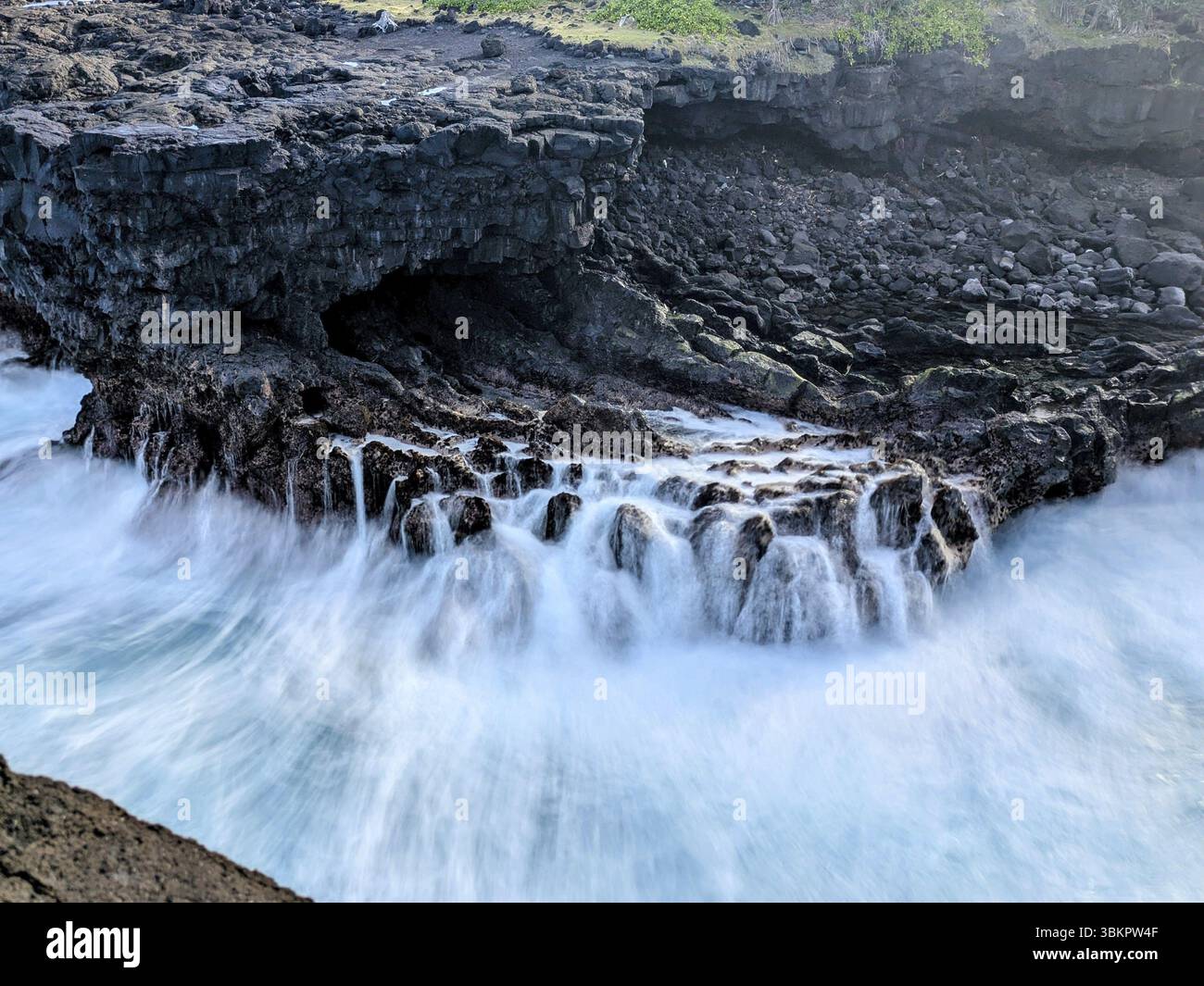 Wellen, die über eine felsige Küste krachen, schaffen eine ruhige und natürliche Atmosphäre, La Réunion, Frankreich, Afrika Stockfoto