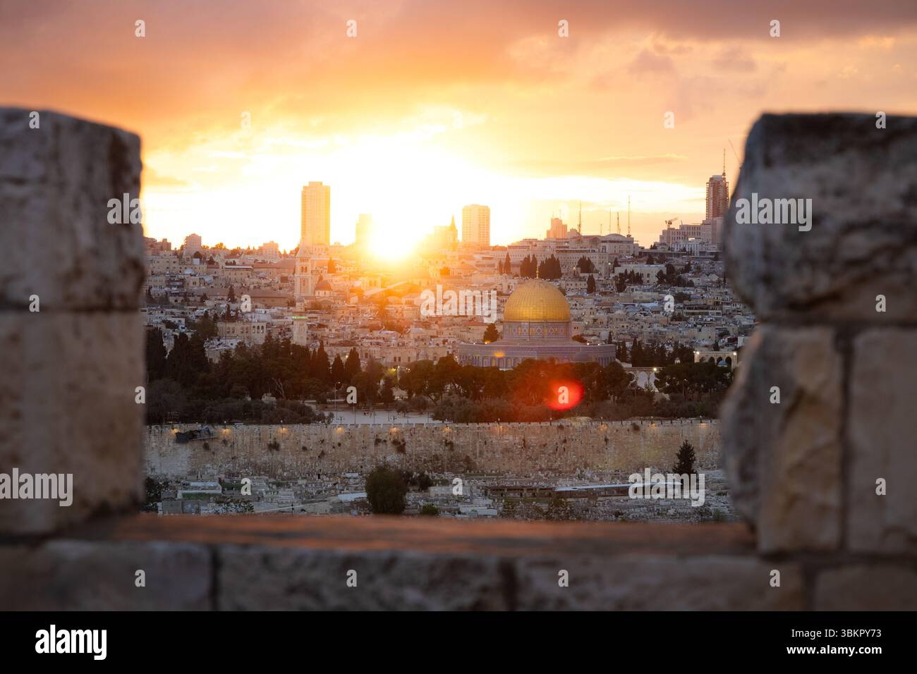 Kuppel des Felsens und die Altstadt von Jerusalem bei Sonnenuntergang, gesehen durch eine Friedhofsmauer auf dem Ölberg Stockfoto