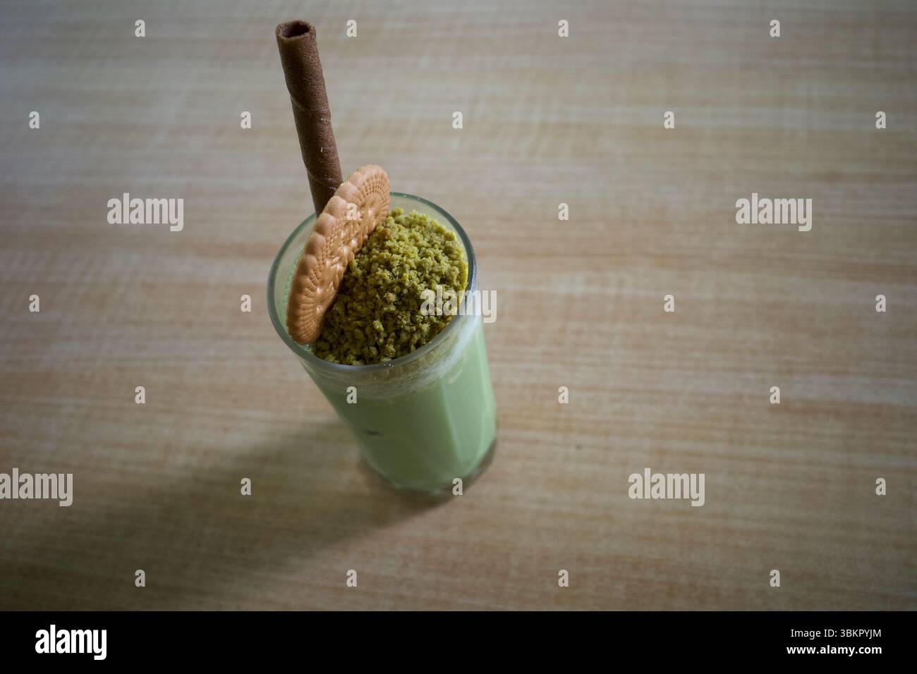 Ein Glas Matcha Green Tea Milchshake, garniert mit einem Keks, einem Keks und einem Waffelstab. Stockfoto
