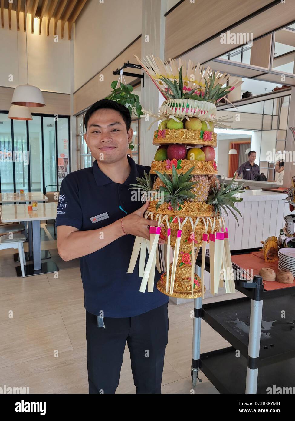 Ein lächelnder junger Kellner präsentiert ein wunderschönes Obst-Arrangement, Harris Hotel, Denpasar, Bali, Indonesien Stockfoto