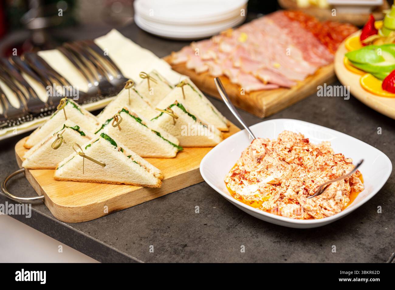 Elegantes Catering-Angebot mit Dreieck-Sandwiches, Paprikaaufstrich, Aufschnitt und frischem Obst für eine Party oder Veranstaltung. Stockfoto