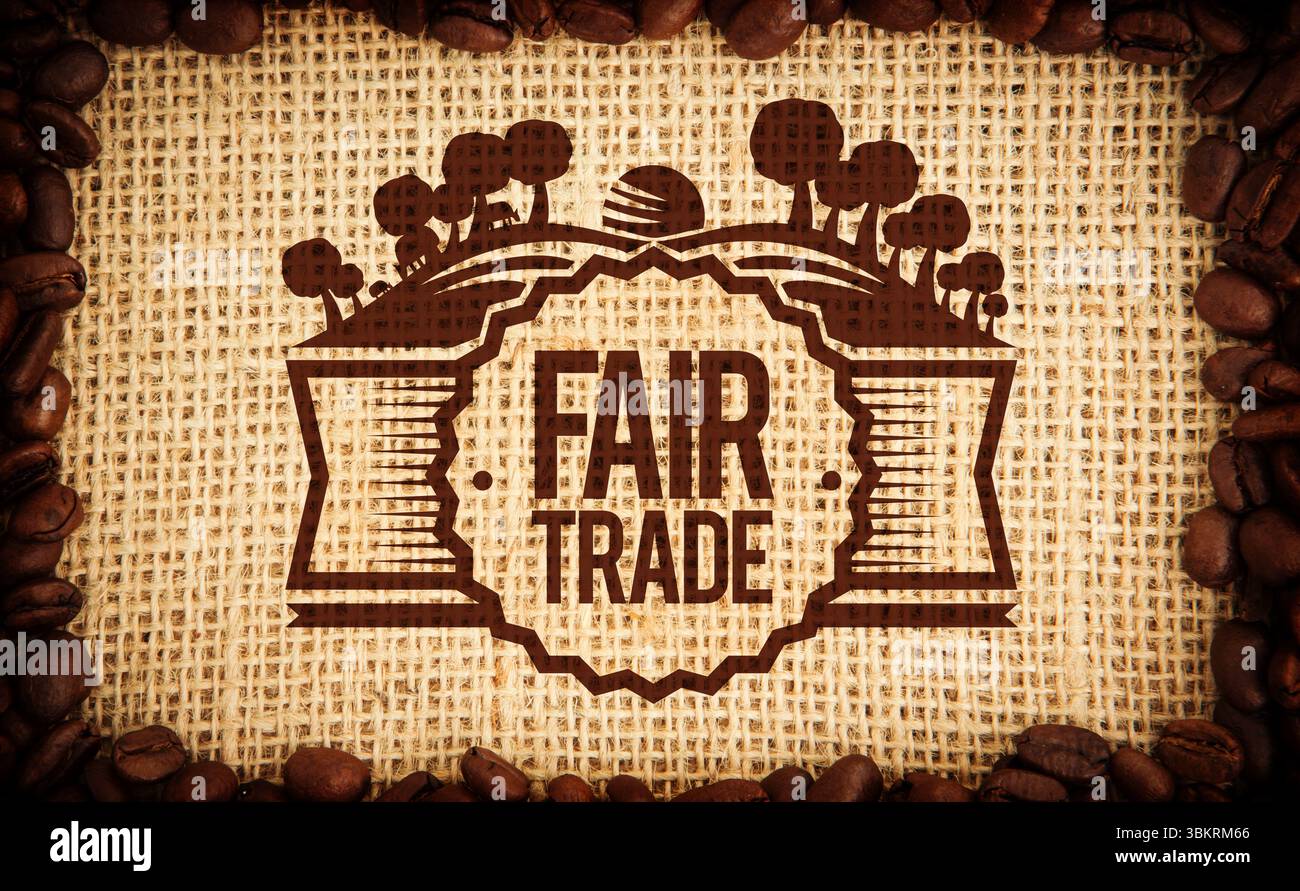 Das Fair-Trade-Emblem hebt sich auf der groben Sackleinen-Ebene hervor, mit den Kanten der Kaffeebohnen Stockfoto
