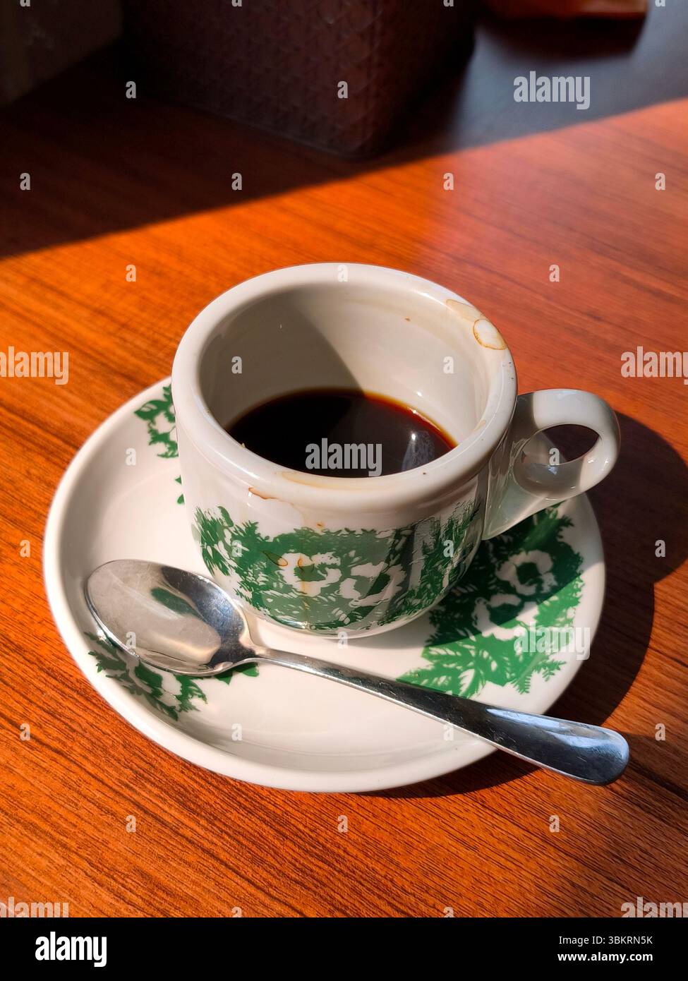 Eine Tasse schwarzen Kaffee, der auf einem Holztisch mit Morgenlicht getrunken wurde Stockfoto