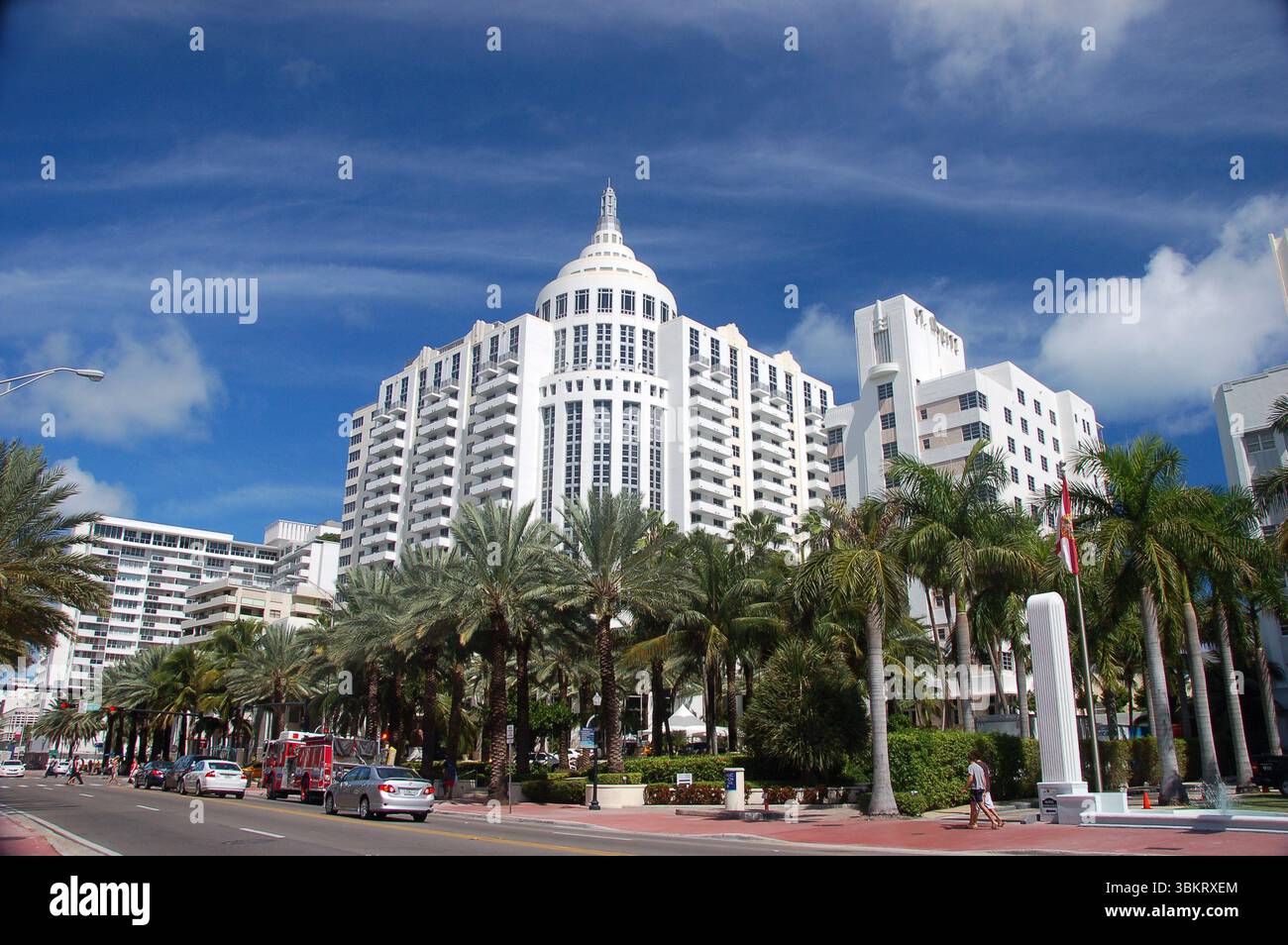 Eleganter weißer Art déco-Wolkenkratzer mit Palmen vor dem Hotel, unter einem klaren blauen Himmel in Miami Beach, Florida, von einem Straßenblick erfasst Stockfoto