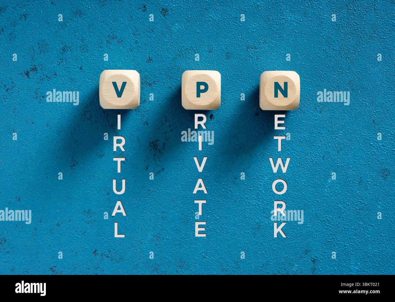 Holzwürfel, die VPN-Akronym für virtuelles privates Netzwerk auf blau strukturiertem Hintergrund verwenden Stockfoto