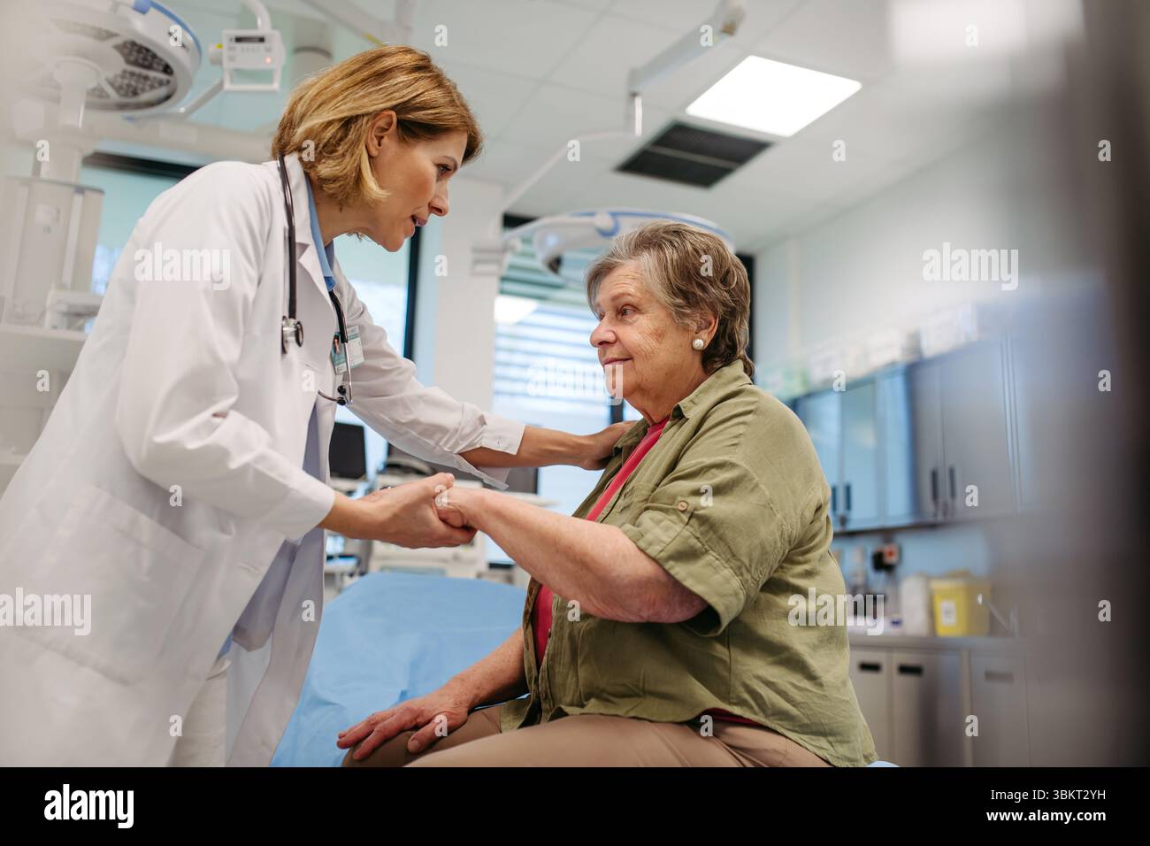 Gütiger Arzt tröstet ältere Patienten mit sanfter Handberührung Stockfoto