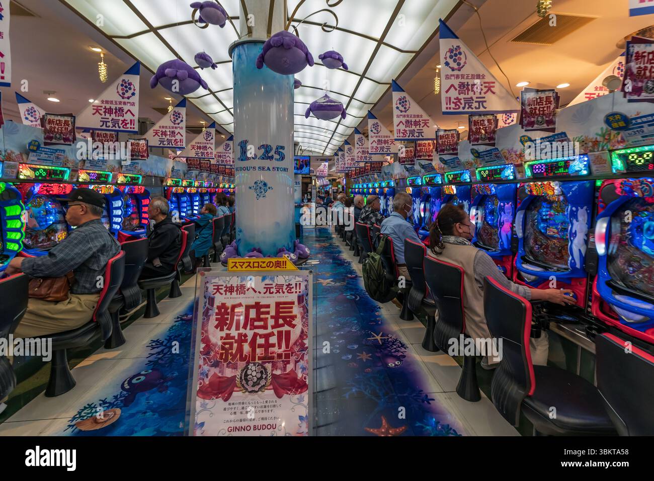 Leute in der Spielautomaten-Arcade von Pachinko in Osaka, Japan. Pachinko ist ein beliebtes Spiel für Freizeit- und Glücksspiele. Stockfoto