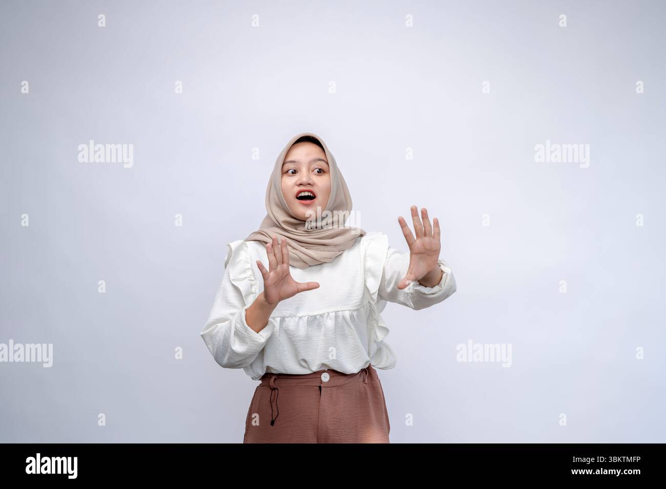 Eine junge indonesische Frau, die Hijab trägt und Stoppschild mit einer Handfläche auf weißem Hintergrund hält Stockfoto