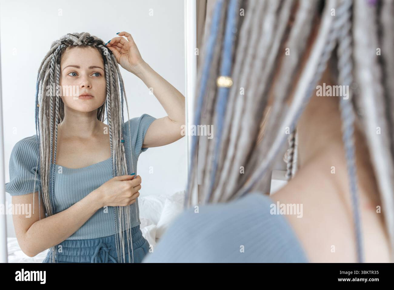 Junge schöne Frau, die in den Spiegel schaut. Stockfoto