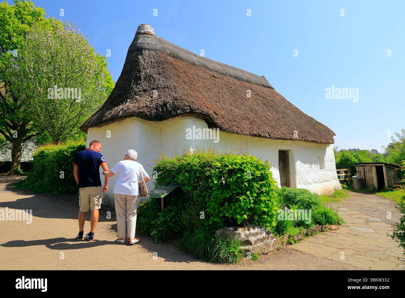 Mann und Frau, die Nantwallter-Strohhütte bewundern. St Fagans National Museum of History, Cardiff. Vom April 2025 Stockfoto